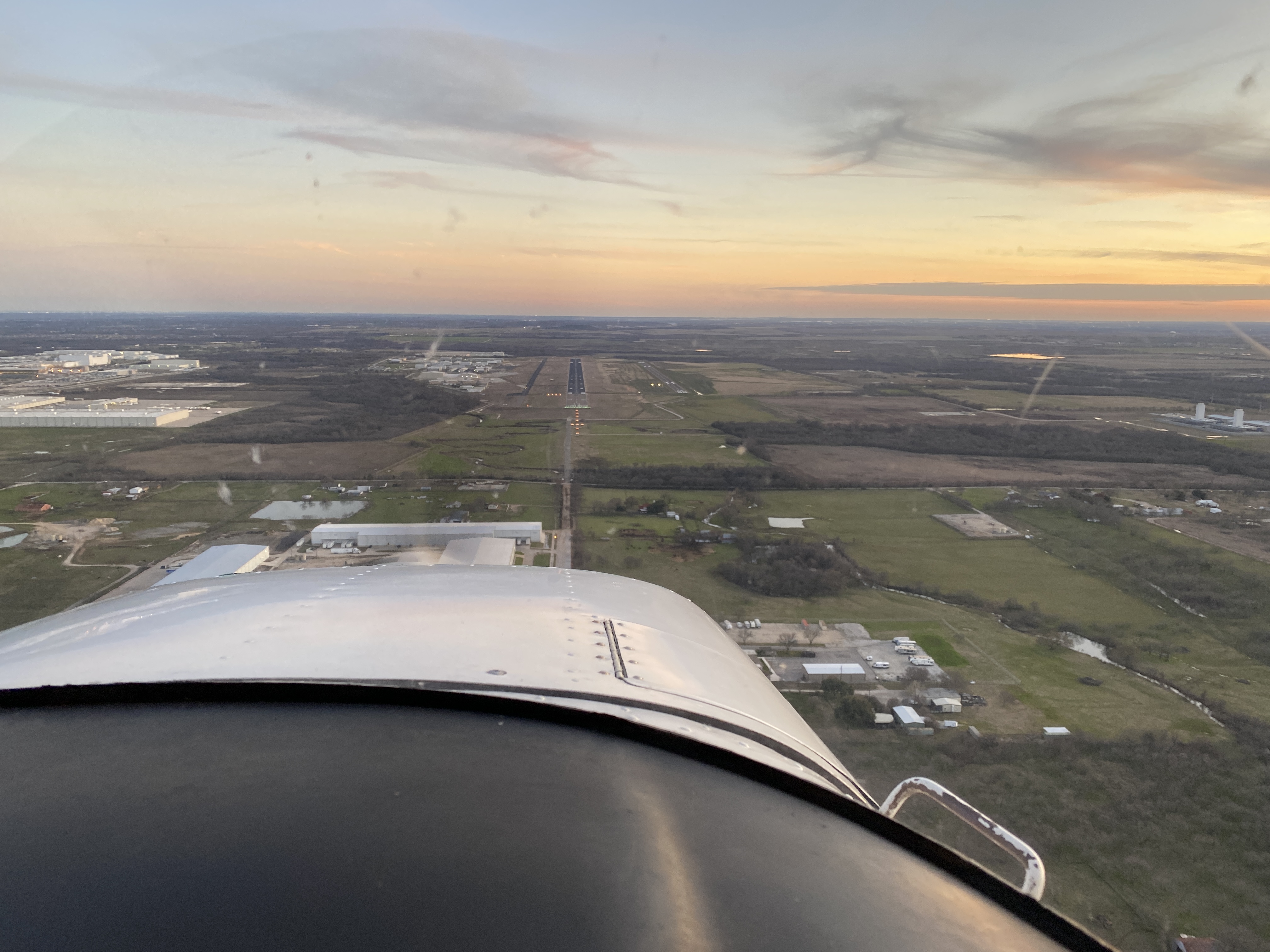 An airport runway viewed ahead through an aircraft windscreen.