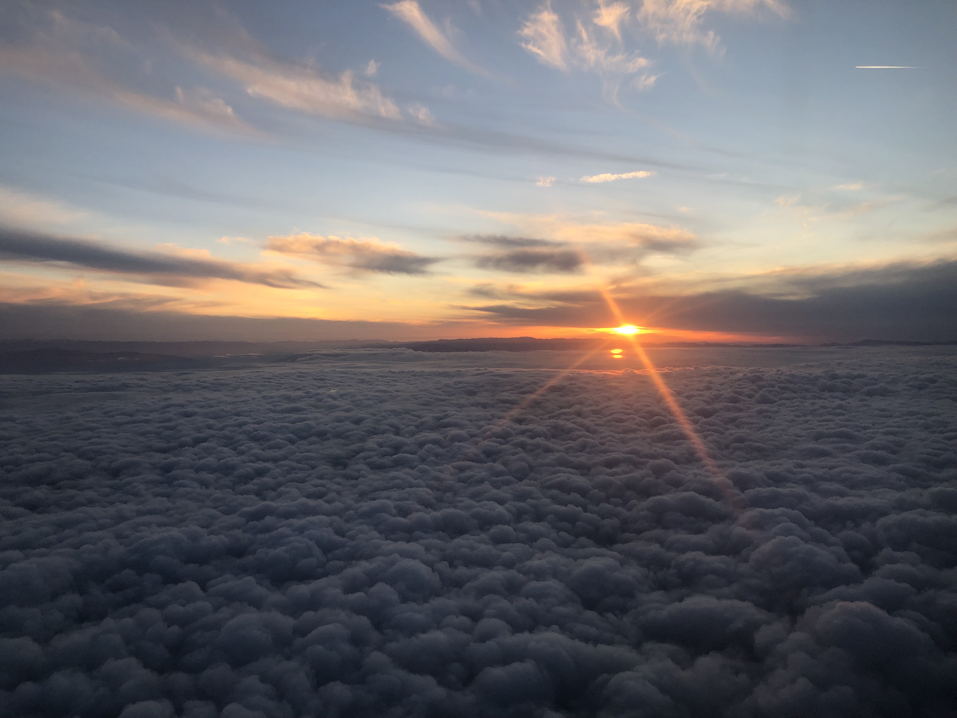 Sunset above a broad layer of clouds during a flight.