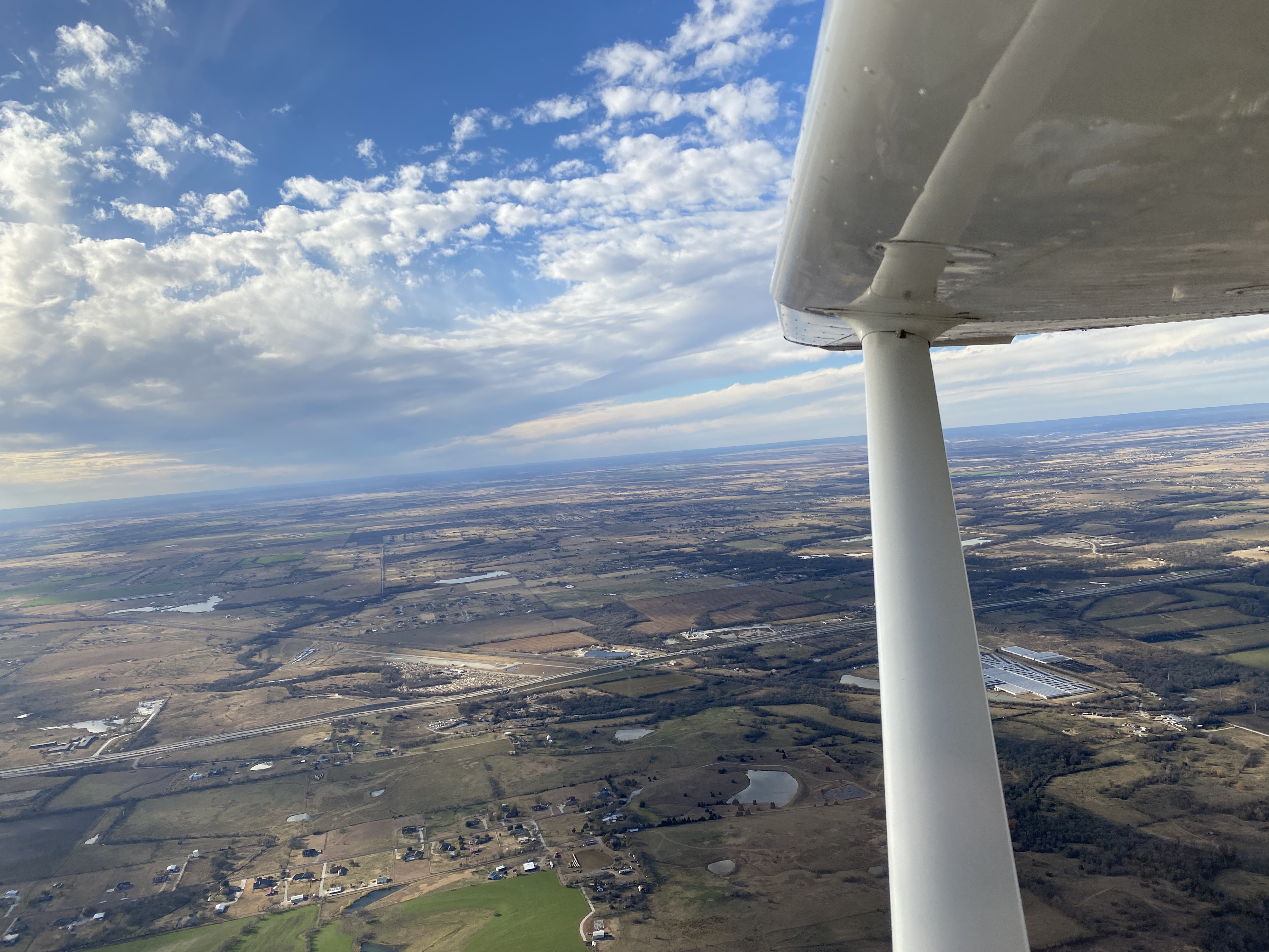 A view across the landscape from beneath an aircraft wing.