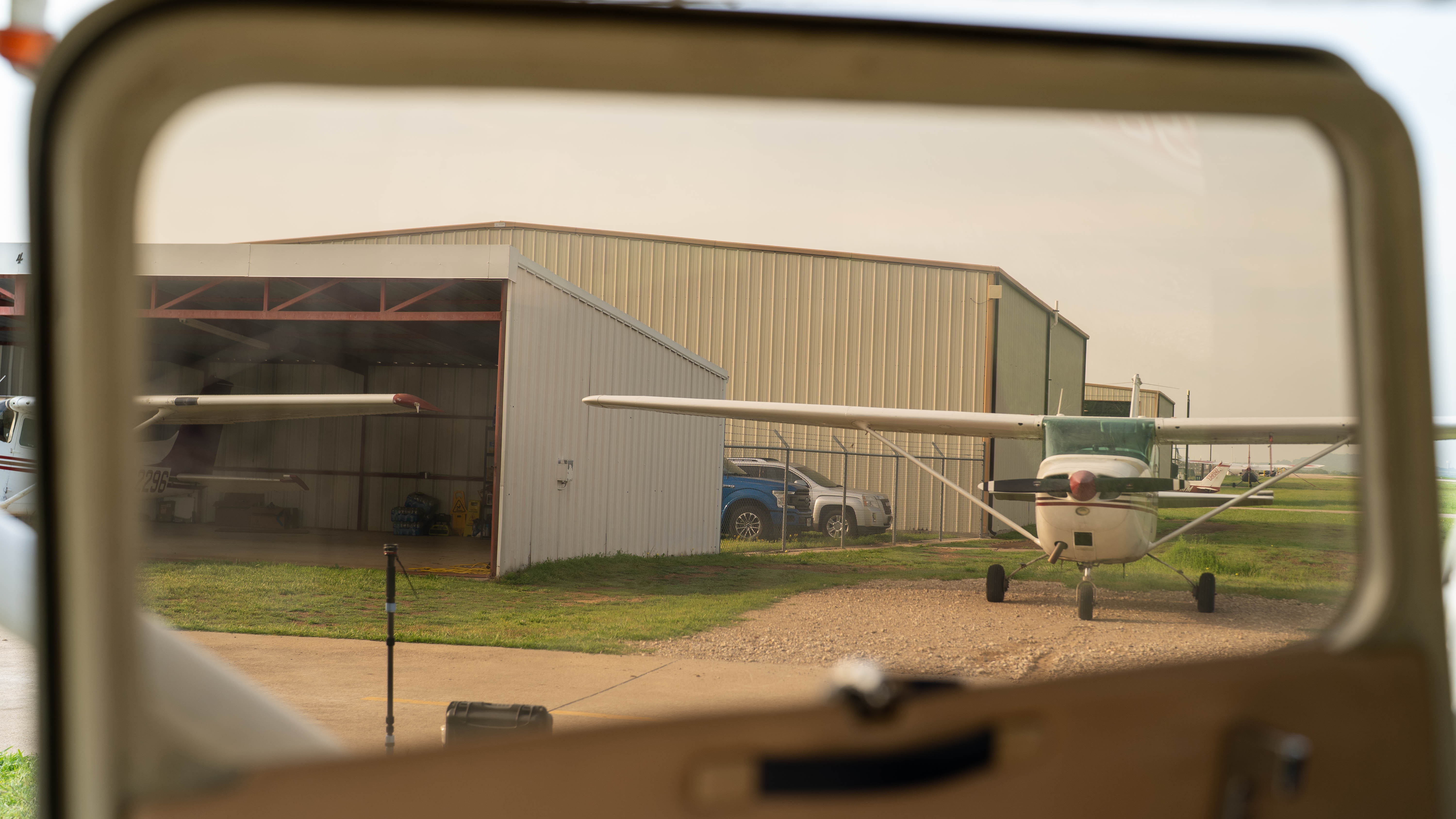 A hangar and aircraft seen through a training aircraft window.