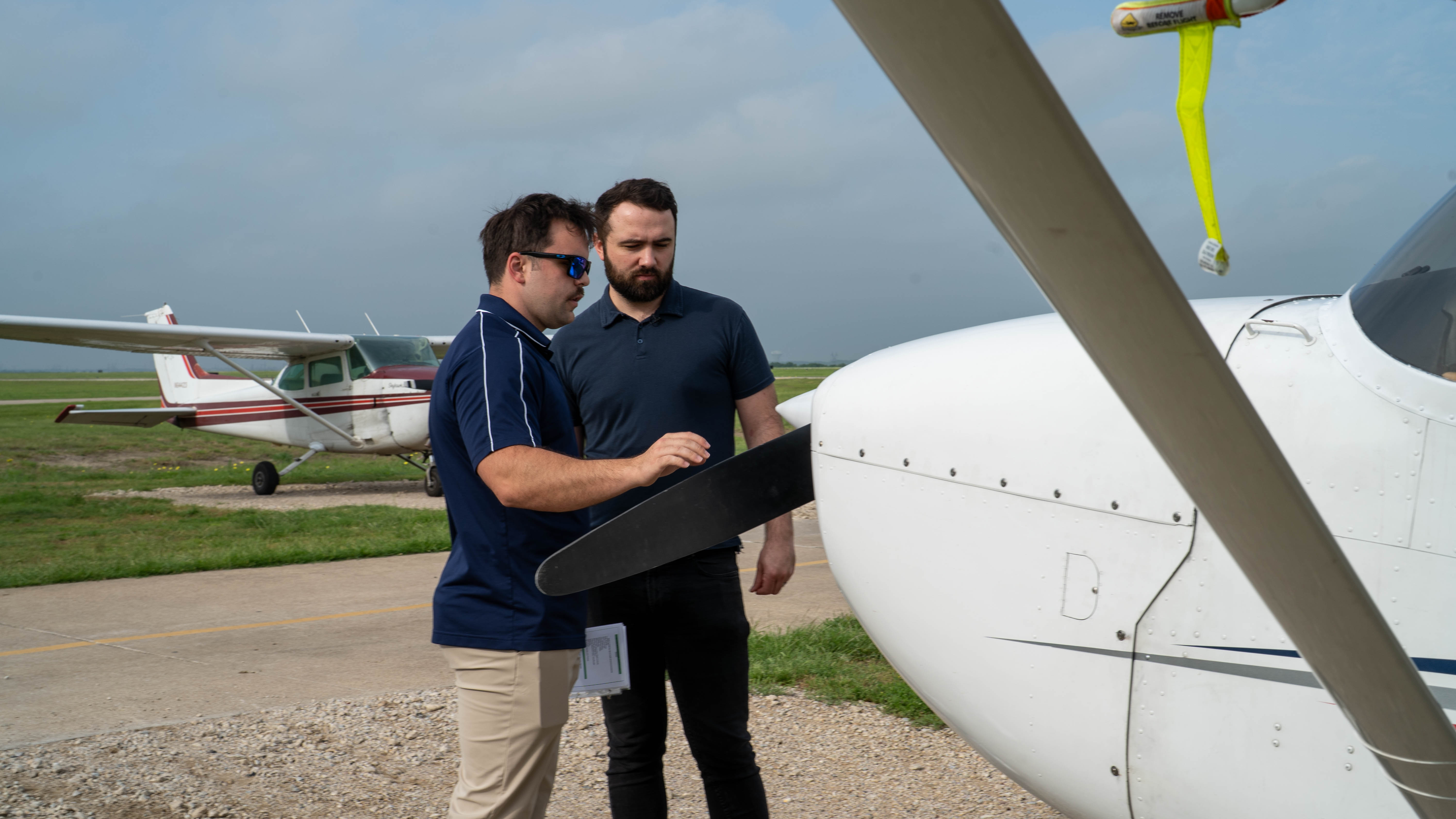 Two people reviewing a checklist beside a training aircraft.