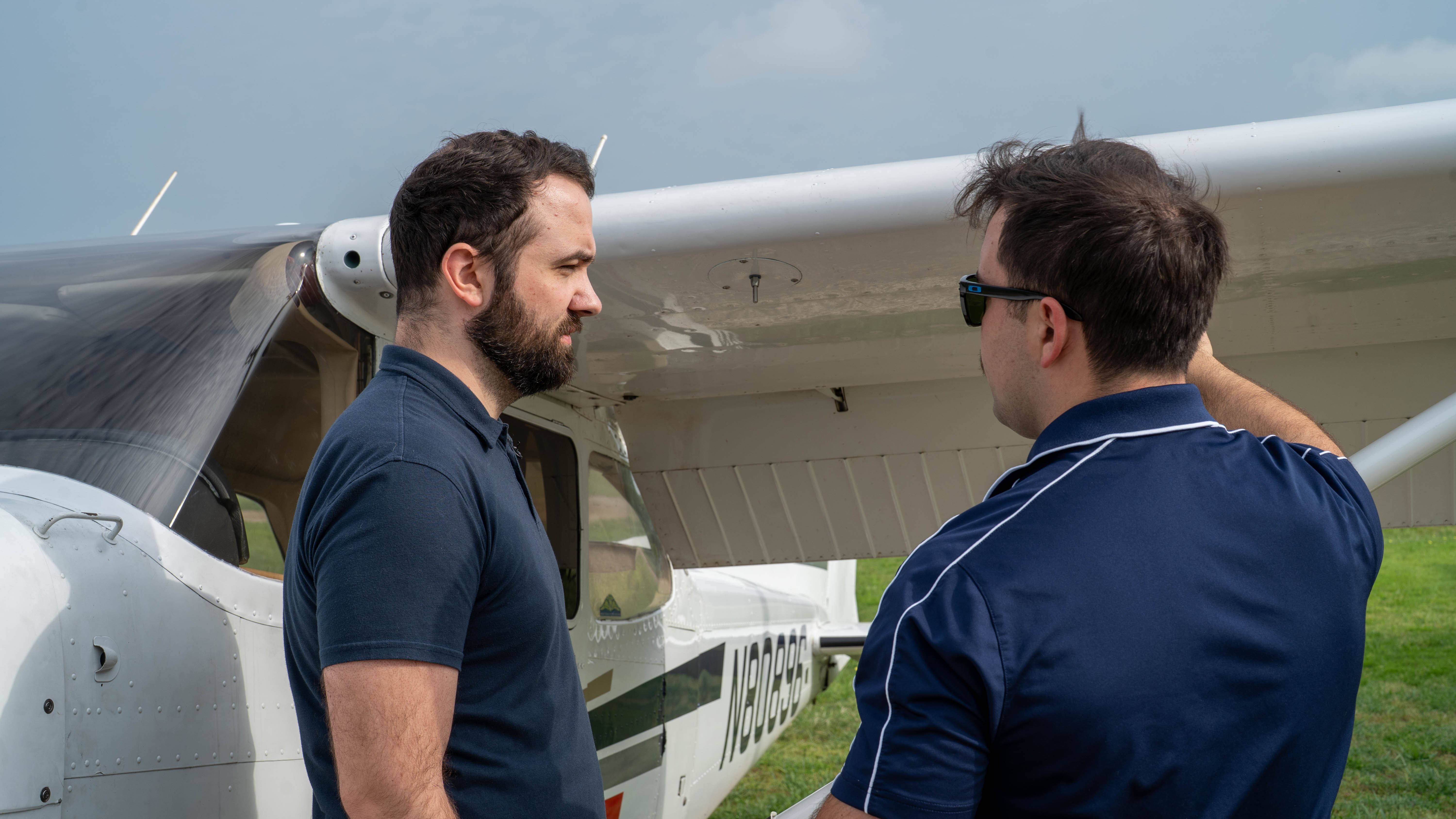 Two people in conversation beside a training aircraft.