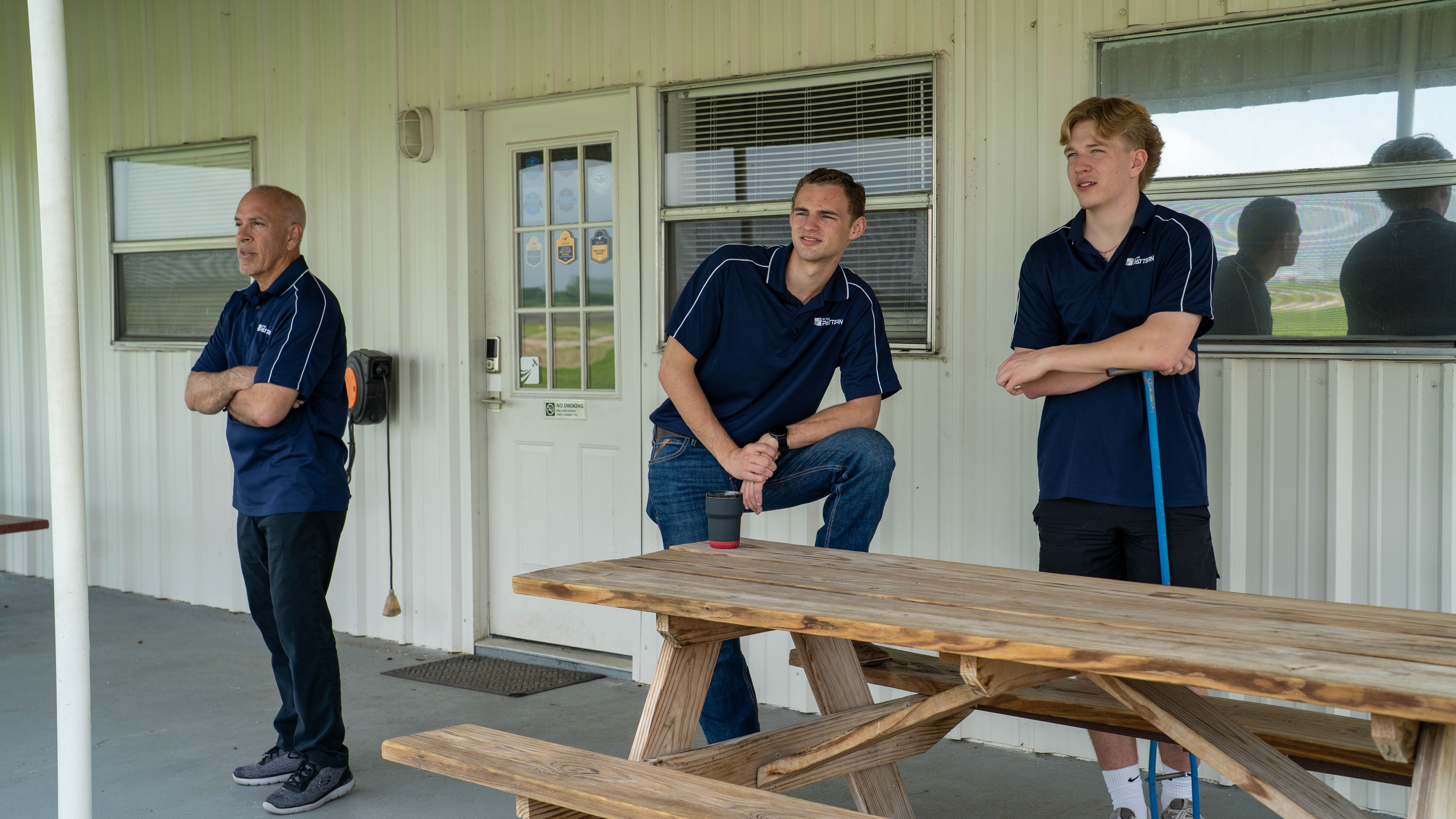People gathered outside the flight school beside a picnic table.