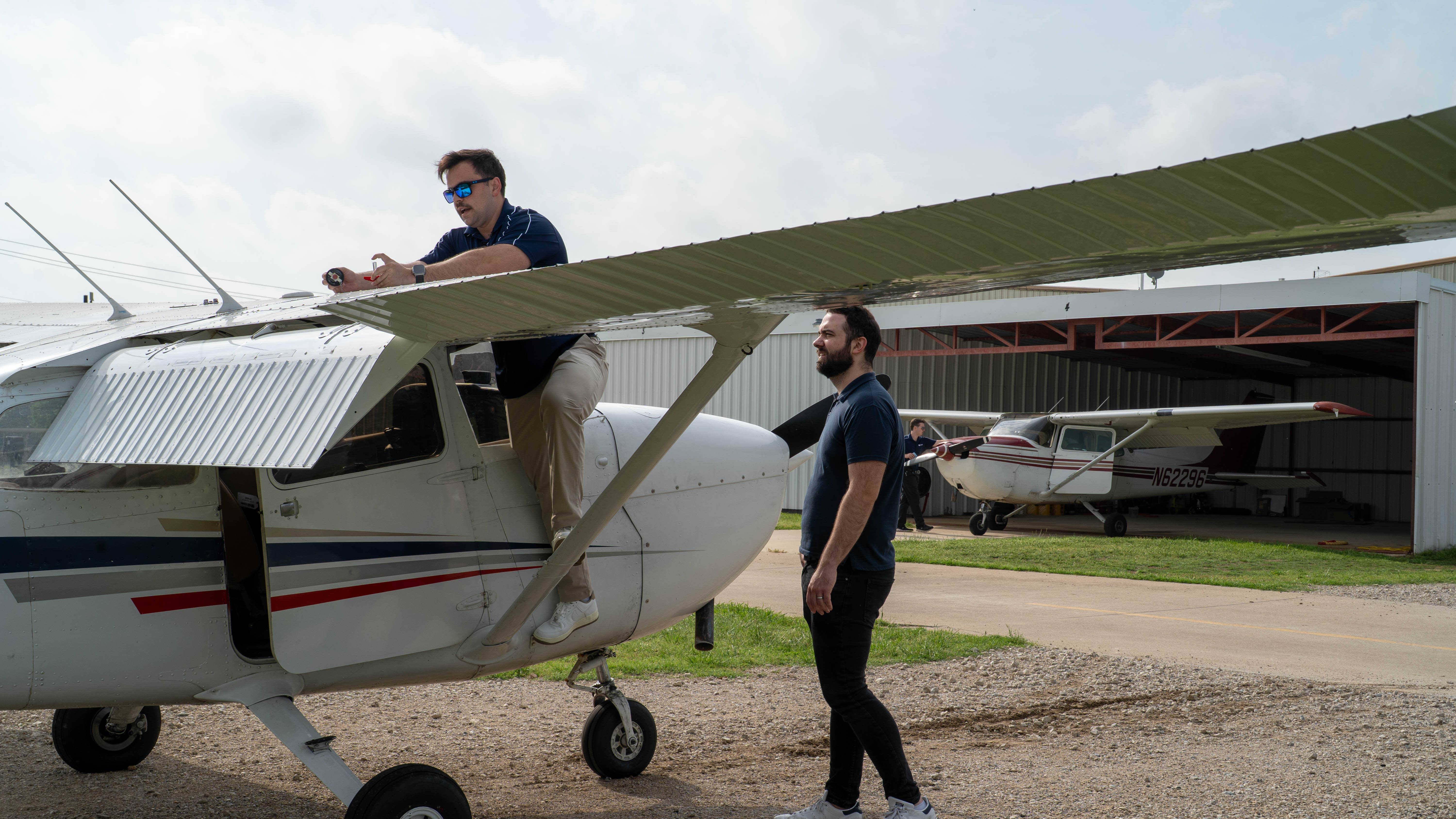 People examining the wing of a training aircraft during a walkaround.