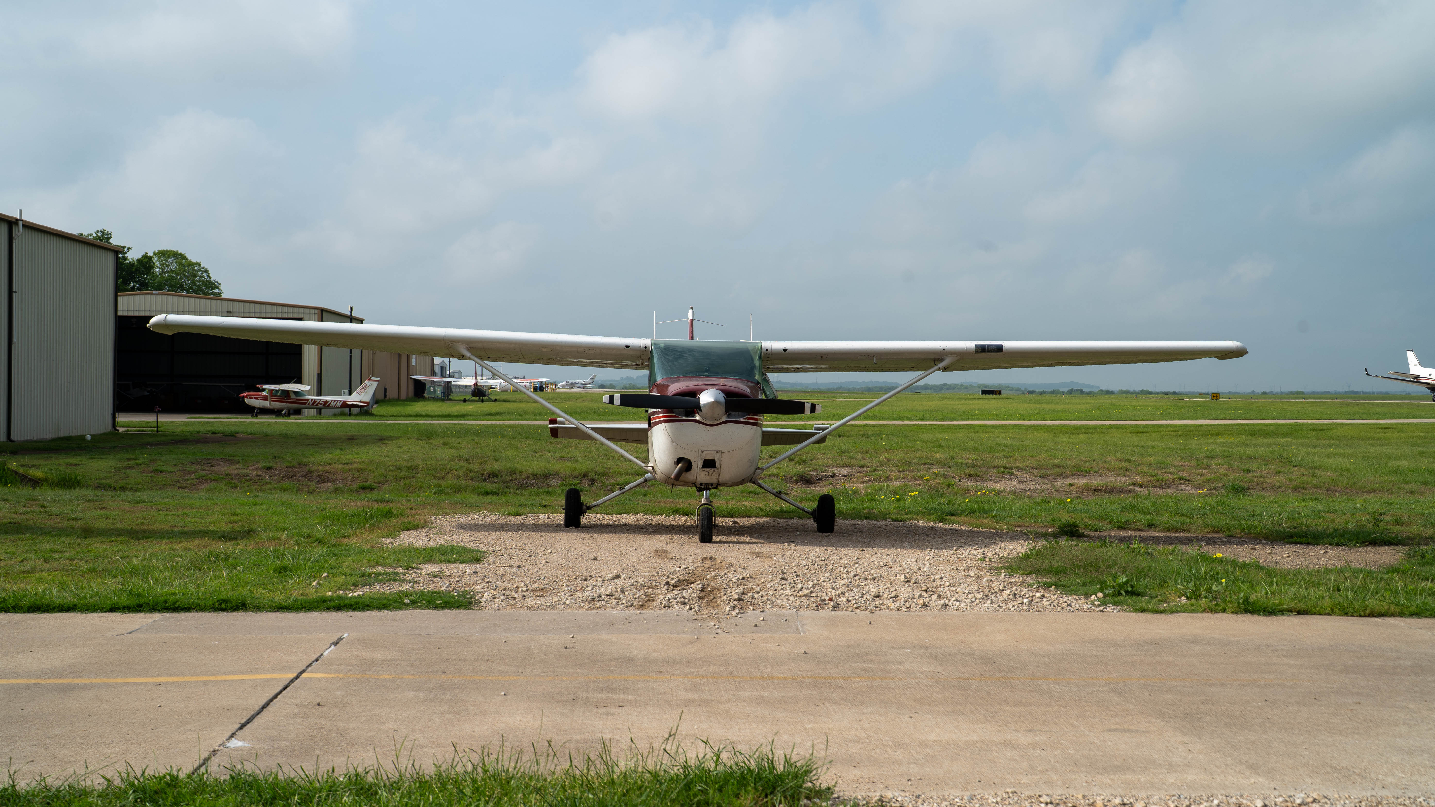A light aircraft on the taxiway outside the hangar.