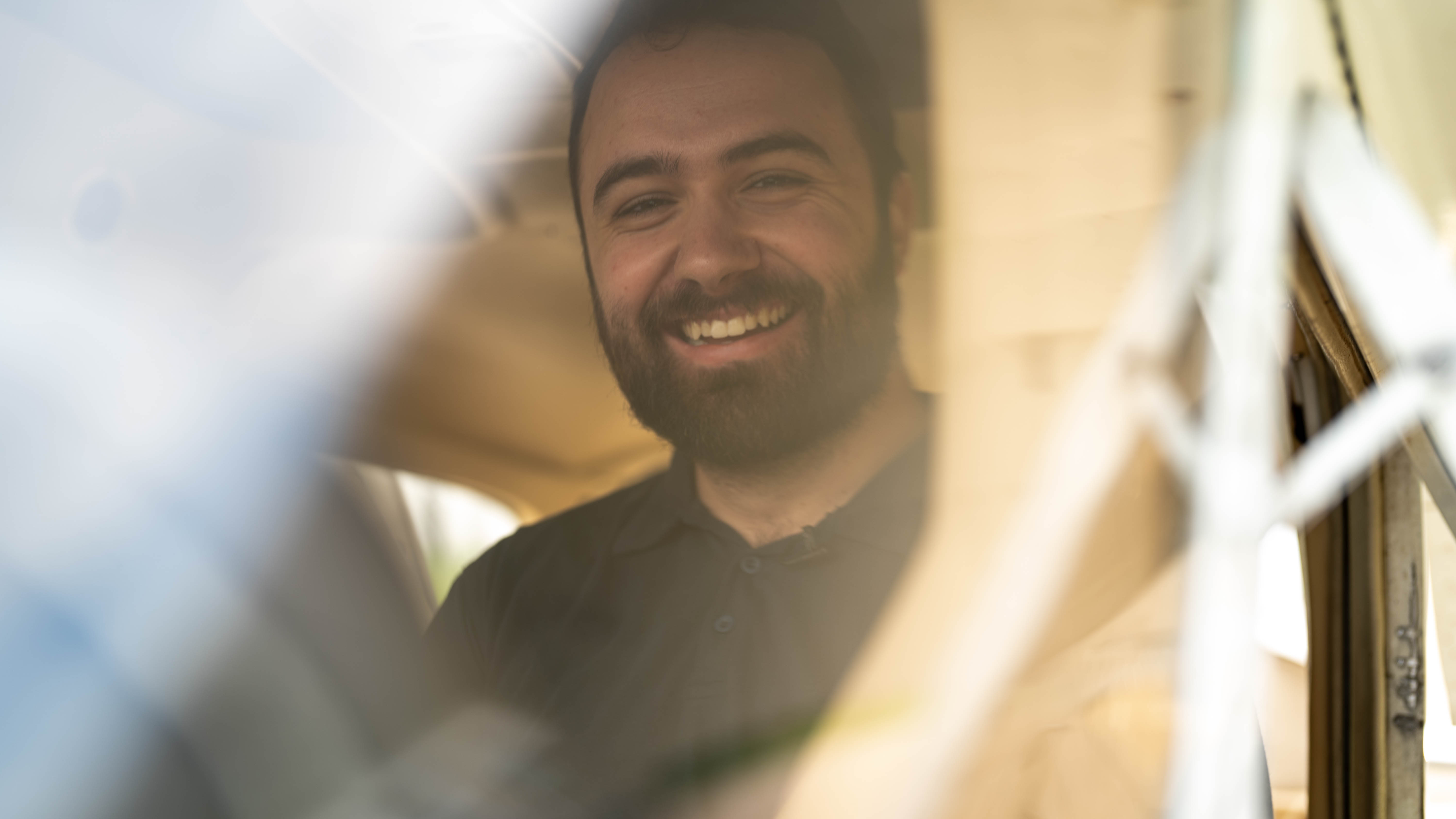 A smiling pilot seen through an aircraft window.