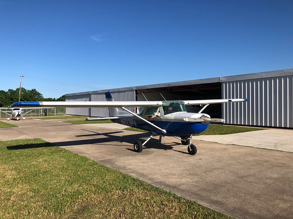 Blue and white Cessna 152 outside the school hangar.